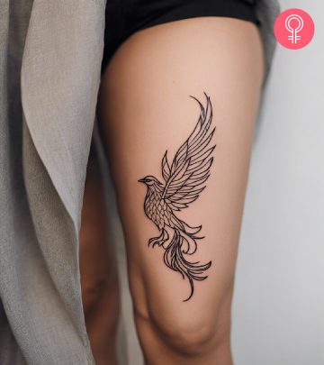 A woman wearing feminine phoenix tattoo on her thigh