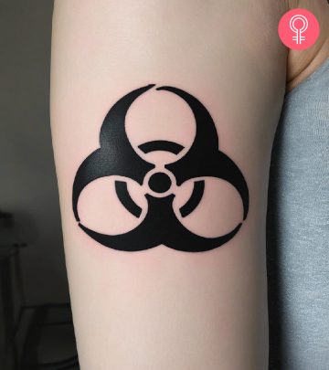 A woman with a black biohazard tattoo on her upper arm
