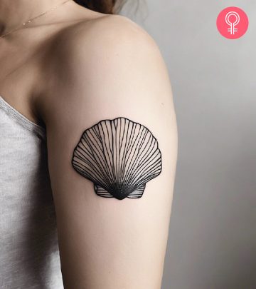 A woman with a black seashell tattoo on her upper arm