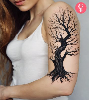 Dead tree tattoo on the upper arm of a woman