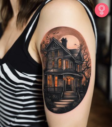 Woman with a haunted house tattoo on the upper arm