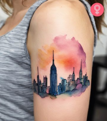 A New York skyline tattoo on the upper arm of a woman