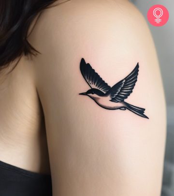 A flying bird tattoo on the upper arm
