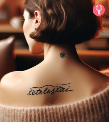 A Tetelestai tattoo on the upper back of a woman