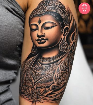 A black and gray Tibetan Buddha inked on the upper arm