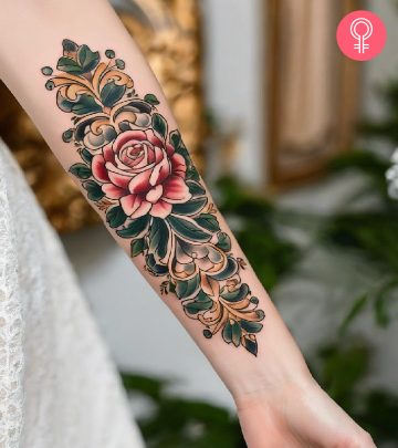 A colorful baroque tattoo with roses and leaves on the forearm