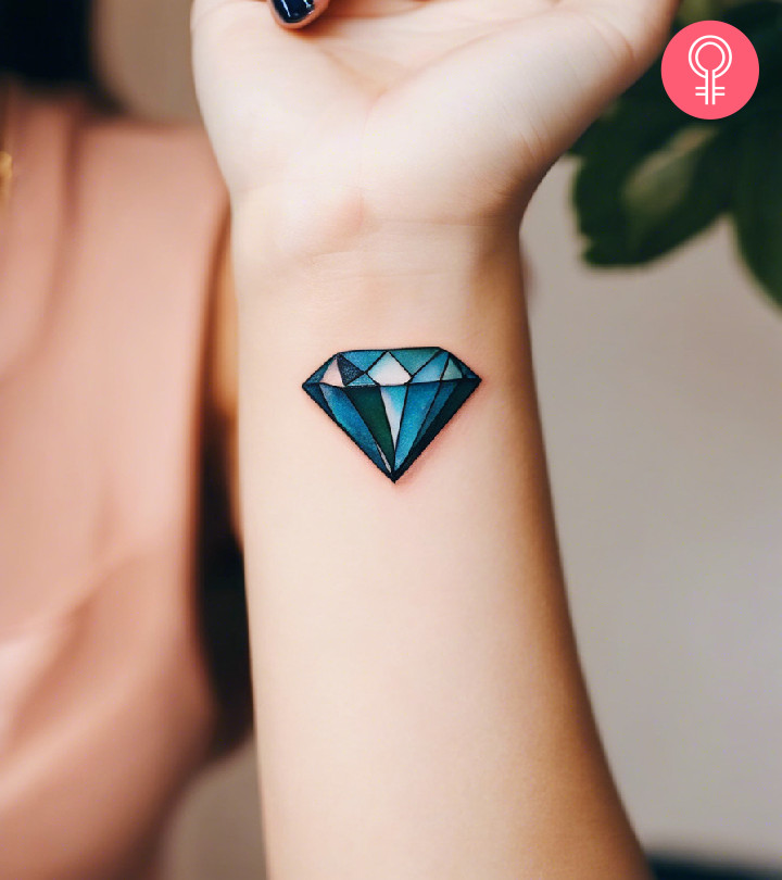 A minimalist wrist tattoo showcasing the green hue of an emerald birthstone, symbolizing May and growth.