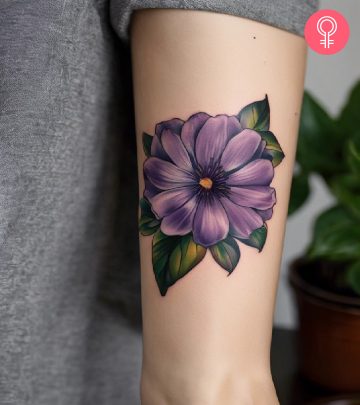 A purple flower tattoo on the arm of a woman