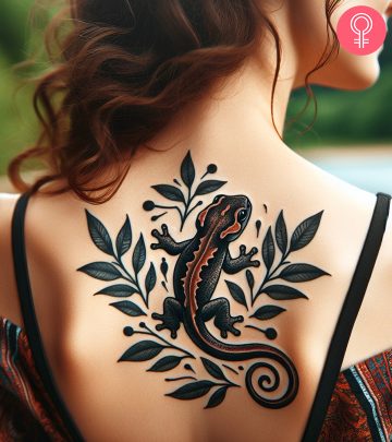A salamander tattoo on the upper back of a woman