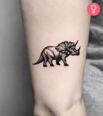 A small triceratops tattoo on the upper arm