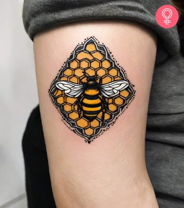 A traditional beehive tattoo on the upper arm of a woman