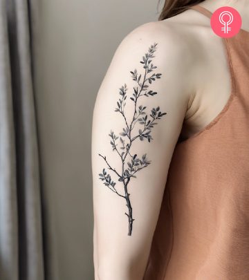 A tree branch tattoo on the upper arm of a woman