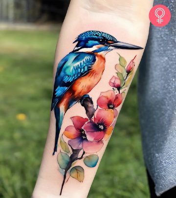 A watercolor kingfisher tattoo on a woman’s arm