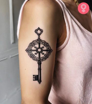 Black line skeleton key tattoo on the upper arm of a woman