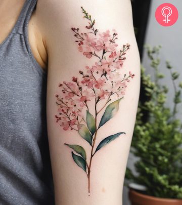 A watercolor tattoo of baby’s breath on a woman’s upper arm