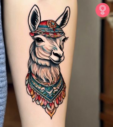 Woman with a traditional llama tattoo with a scarf and a headdress inked on the forearm