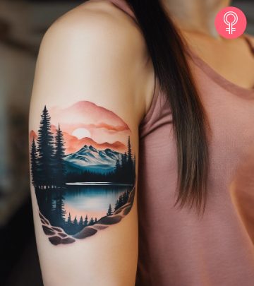 A woman with a colored mountain and trees scenery tattoo on her upper arm