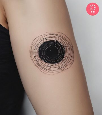 A woman with a black hole tattoo on her upper arm