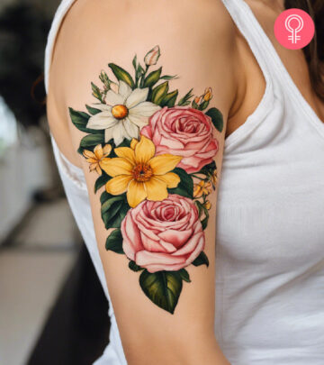 A woman wearing a ‘family birth flower bouquet’ tattoo on the upper arm.