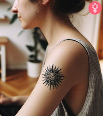 Black sun and leaves tattoo on the upper arm